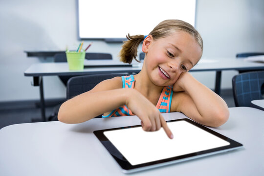 Happy girl using digital tablet in classroom