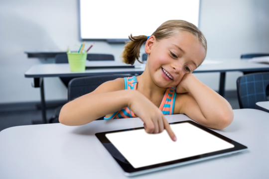 Happy girl using digital tablet in classroom