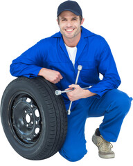 Mechanic leaning on tire while holding wheel wrenches