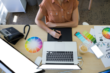 Midsection of businesswoman using graphic tablet at desk in office