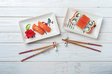 sushi and rolls with salmon on plates on a wooden white background for an online restaurant menu