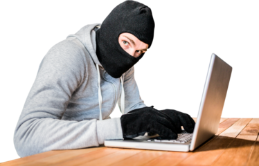 Focused thief with hood typing on laptop
