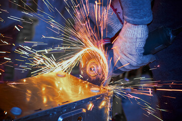 A worker cuts the case of a personal computer with a grinder. Sparks draw tracks. Hacking a...