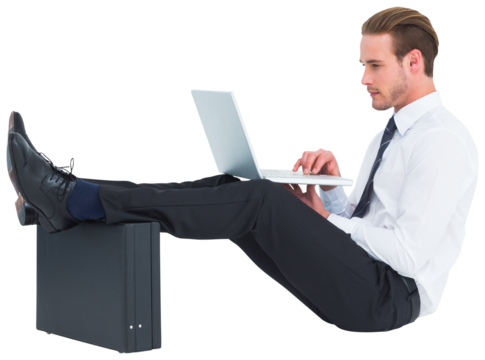 Businessman using laptop with feet up on briefcase - Powered by Adobe
