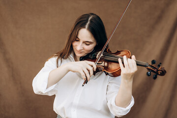 A beautiful girl holds a violin in her hands. Violinist in white shirt and jeans