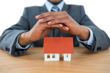 Businessman protecting house model with hands