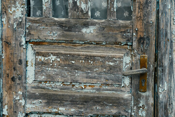 Close up shot of an old abandoned wooden door and its handle with peeling blue paint.