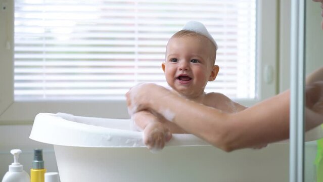 Cute healthy six month old baby bathing with foam and soap bubbles