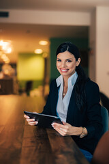 Portrait of a smiling businesswoman holding a tablet, sitting at the workplace.