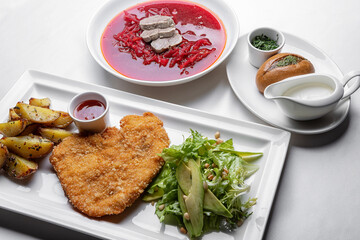 Hearty Eastern European Meal: Beef Schnitzel, Red Borscht, and Sides