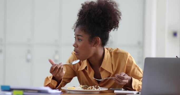 African American woman have lunch with fast food in office.
