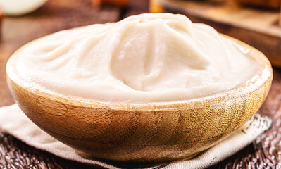 wooden bowl with lard, pork fat used as a brazilian cooking ingredient, bacon and pork sausage in the background, macro photography