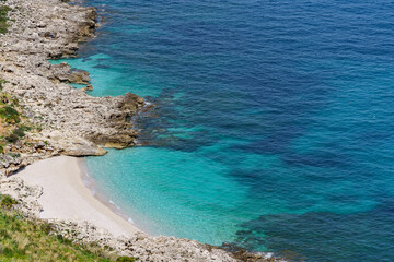 Fototapeta na wymiar Beautiful stone beach flowing into the wonderful turquoise sea, seen from high mountains.