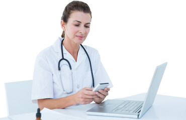Female doctor using mobile phone with laptop on table