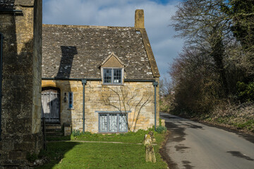 Medieval stone built wall of countryside house with windows in Cotswolds England