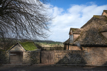 Old stone built wall and house in Cotswolds, England