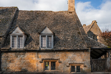 Obraz premium Detail of old traditional windows and roof tiles of stone built cottages in Cotswolds England