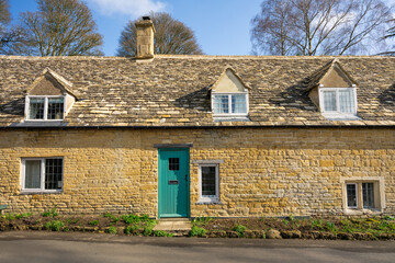 Fototapeta na wymiar Medieval stone built traditional cottage with green door at Snowshill in Cotswolds, England