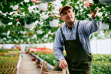 Small business owner taking care of flowers in greenhouse.