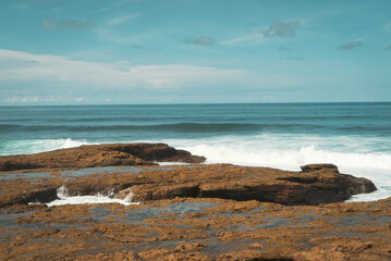 exposed rock coastline along the Pacific ocean with white foam on the waters surface as the rough surf agitates and oxygenates the sea water and sprays a fine salty mist into the air