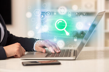 Hands working on laptop with digital icons