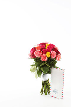 Bouquet of roses on a white background. An envelope with a letter. Vertical photo. Isolated object. The concept of the holiday.