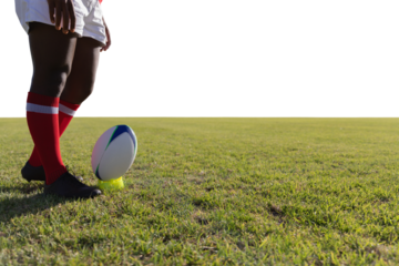 Rugby player preparing to kick the ball on field.