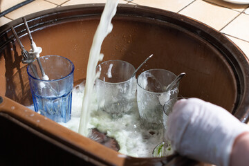 woman washing dishes in the sink with gloves with detergent