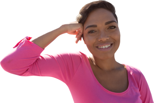 Smiling woman standing for breast cancer awareness against white background