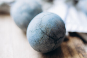 Stylish easter eggs in rustic nest or desk on table. Natural dyed colorful easter eggs with feathers on rural textile background. Happy Easter.