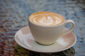 Barista concept, White coffee cup and saucer on the table, Hot cappuccino or latte art with heart-shaped milk foam on top, Outdoor drinking coffee at the cafe' in the afternoon, Beverage background.