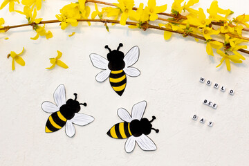 Handmade paper bees with Forsythia flowers on white background. World bee day on 20th of May.