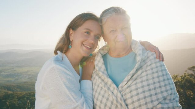Portrait of two women young and elderly. Young woman hugs senior caucasian woman outdoor at sunrise. Models look into the camera