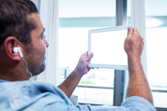Man holding digital tablet against window