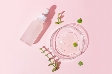 Cosmetic jar with a white cap and a pipette on a pink background. Petri dish with gel on a pink background. Surrounded by plants.