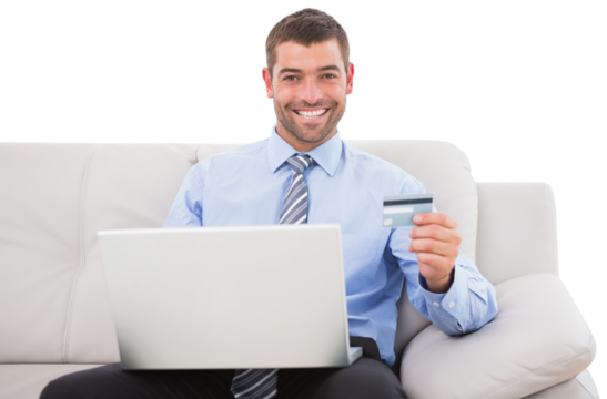 Smiling businessman with credit card and laptop sitting on sofa - Powered by Adobe