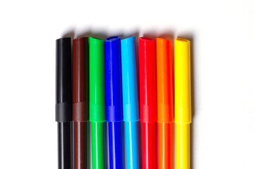 Fototapeta premium Markers of different colors lie in a row. On a white background.