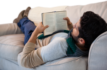 Full length of man lying on sofa while reading book