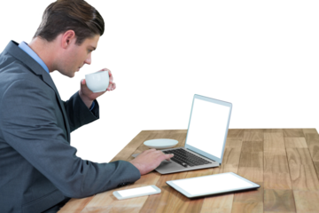 Businessman having coffee while using laptop