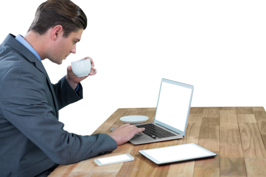Businessman having coffee while using laptop 