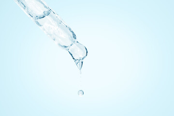 Cosmetic pipette with dripping liquid and drops on the south, blue background, serum, serum, gel, vitamin, water, oil.