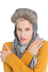 Woman in winter clothes shivering over white background