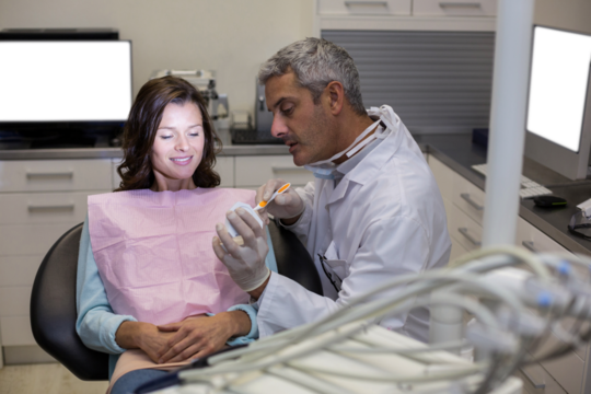 Dentist showing mouth model to female patient