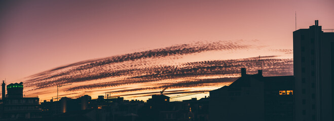 Stunning and dramatic panoramic sunset in Lisbon, with shades of pink transitioning to a yellowish...
