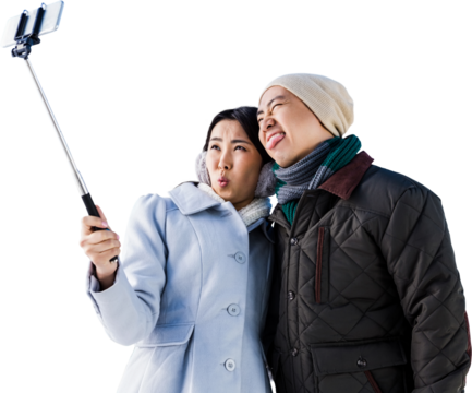 Playful couple taking selfie against building