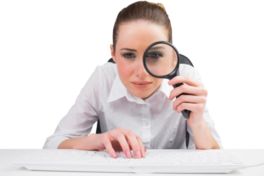 Businesswoman typing and looking through magnifying glass