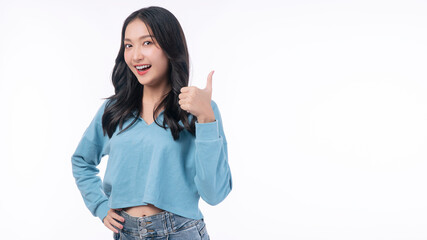 Obraz premium Excited asian woman showing thumbs up gesturing winner or good product smiling teeth over isolated white background.Confident positive young girl holding thumb up like approving sign success copyspace