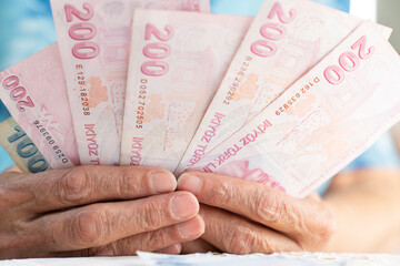 old women hands holding Turkish Lira banknotes
