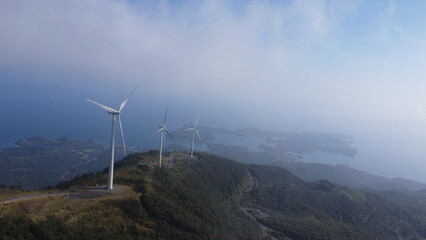 Windmills. Windmill farm. Wind turbines on top of a mountain among the clouds.