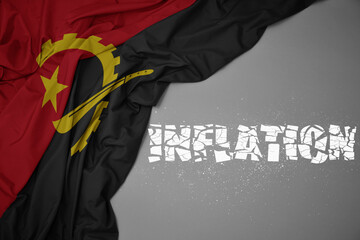 waving colorful national flag of angola on a gray background with broken text inflation. 3d...